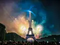 Espectacular espectáculo de fuegos artificiales ilumina la Torre Eiffel, celebrando porque se celebra el 14 de julio en Francia. Multitud observa.
