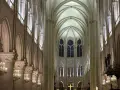 Interior de Notre Dame, con sus impresionantes arcos góticos, vitrales y candelabros dorados. Las **entradas Notre Dame** se abren a este majestuoso espacio.