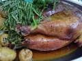 Pollo de Bresse asado, dorado y jugoso, acompañado de patatas pequeñas y hierbas frescas.