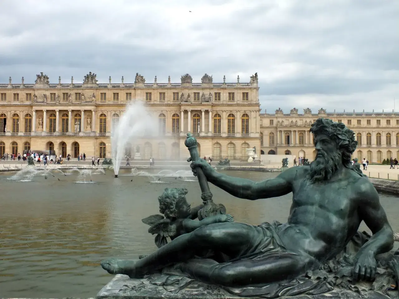 Estatuas de bronce y fuentes frente al majestuoso palacio de Versalles.