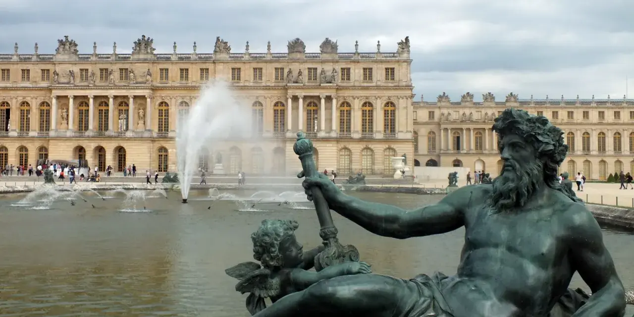 Estatuas de bronce y fuentes frente al majestuoso palacio de Versalles.