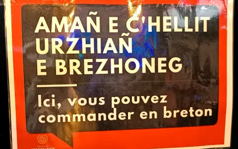 Cartel en bretón y francés: "Aquí puedes pedir en bretón". Un festival en Bretaña, Francia.