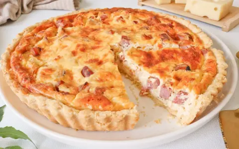 Quiche Lorraine dorada y apetitosa, con trozos de tocino y queso, lista para ser disfrutada.