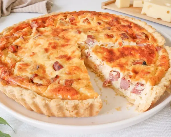 Quiche Lorraine dorada y apetitosa, con trozos de tocino y queso, lista para ser disfrutada.