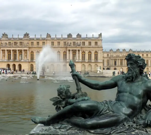 Estatuas de bronce y fuentes frente al majestuoso palacio de Versalles.