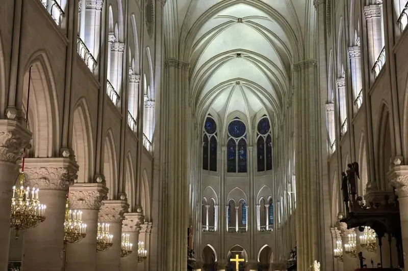 Interior de Notre Dame, con sus impresionantes arcos góticos, vitrales y candelabros dorados. Las **entradas Notre Dame** se abren a este majestuoso espacio.