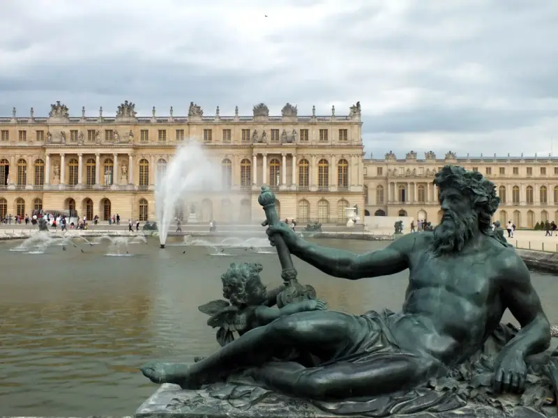 Estatuas de bronce y fuentes frente al majestuoso palacio de Versalles.